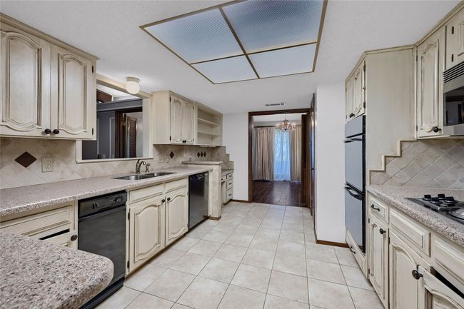 Kitchen with cream cabinetry, dishwasher, a sink, cooktop, and a notable chandelier | Image 16