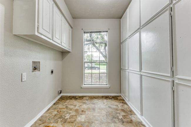Laundry room with cabinet space, electric dryer hookup, washer hookup, and stone finish flooring | Image 14