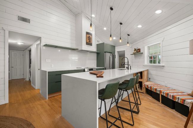 Kitchen with visible vents, stainless steel appliances, a sink, wooden ceiling, and a kitchen breakfast bar | Image 9
