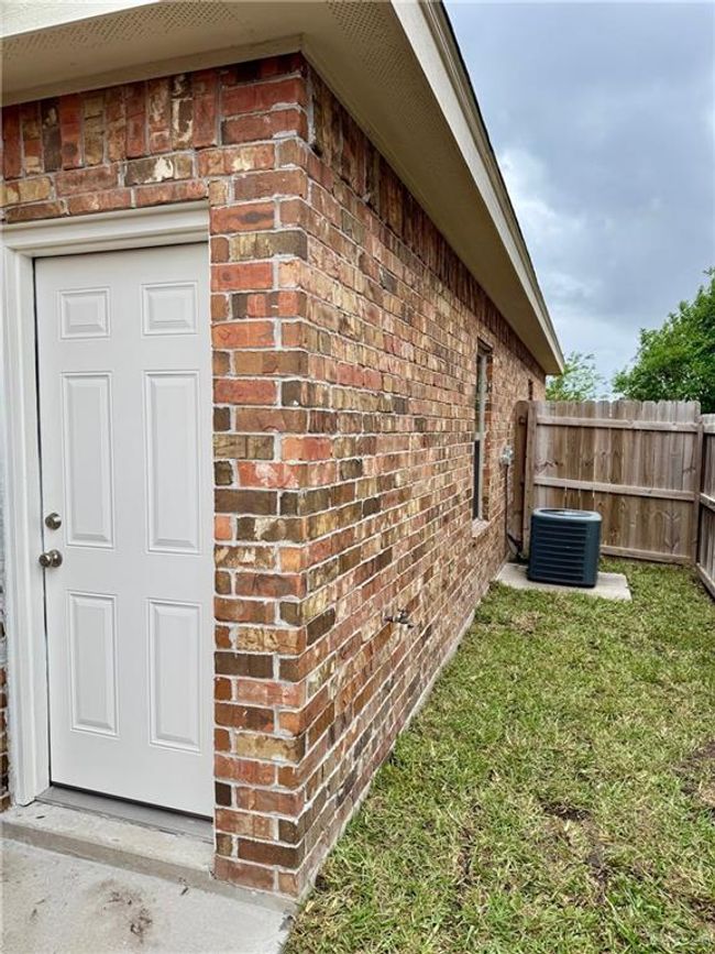 View of home's exterior featuring fence, central AC, a yard, and brick siding | Image 13