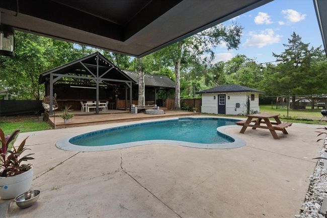 Inviting pool area with expansive party pavilion, hanging lights, and outdoor dining. | Image 9
