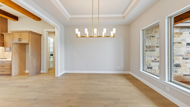 Unfurnished dining area featuring light wood-style flooring, a raised ceiling, a chandelier, and ornamental molding | Image 14