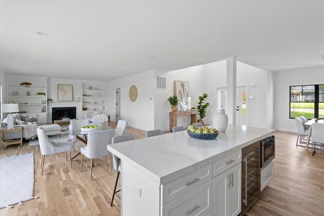 Kitchen with built in microwave, white cabinetry, a center island, a kitchen breakfast bar, and beverage cooler | Image 13