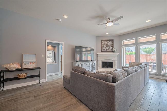 The spacious living area features a stunning cast stone fireplace, creating a warm and lovely focal point for relaxing or entertaining. | Image 13