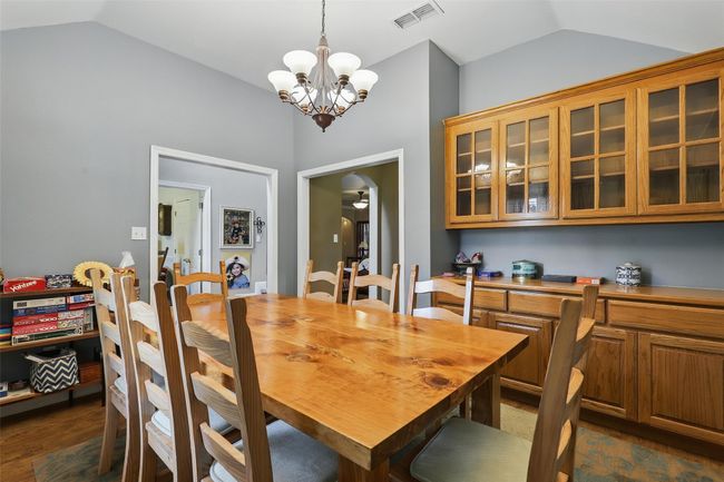 Dining space with lofted ceiling, a chandelier, ceiling fan, and dark wood-style floors | Image 9