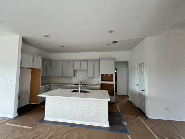 Kitchen with a kitchen island with sink, decorative backsplash, and gray cabinetry | Image 6