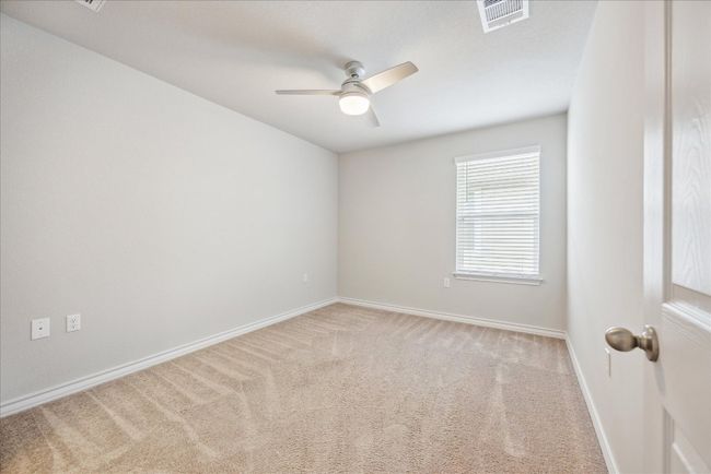 Carpeted empty room featuring visible vents, a ceiling fan, and baseboards | Image 16