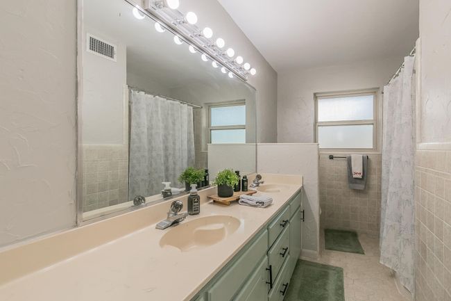 Full bath with double vanity, tile walls, tile patterned floors, and curtained shower | Image 15