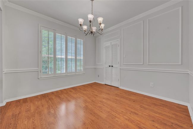 Empty room featuring a chandelier, light wood-style flooring, and crown molding | Image 9