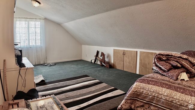 Bonus room featuring a textured ceiling, carpet flooring, lofted ceiling, a textured wall, and baseboards | Image 52