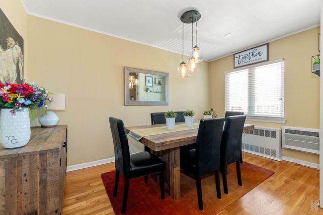Dining area featuring radiator, crown molding, wood finished floors, baseboards, and an AC wall unit | Image 5