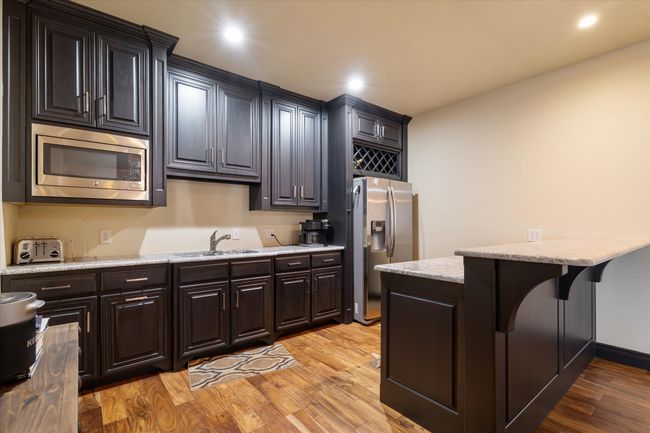 Kitchen featuring appliances with stainless steel finishes, light wood-style flooring, a breakfast bar area, recessed lighting, and light stone counters | Image 13
