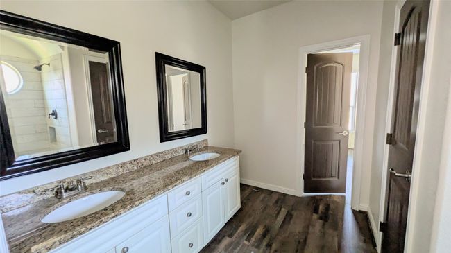 Bathroom featuring double vanity, wood finished floors, a sink, and baseboards | Image 8