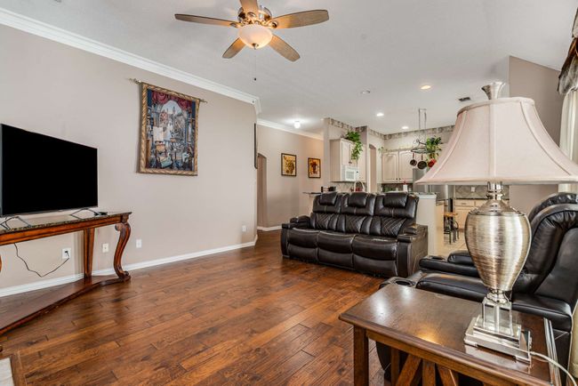 Living room featuring ceiling fan, ornamental crown molding, hardwood flooring, baseboards, and recessed lighting. | Image 21