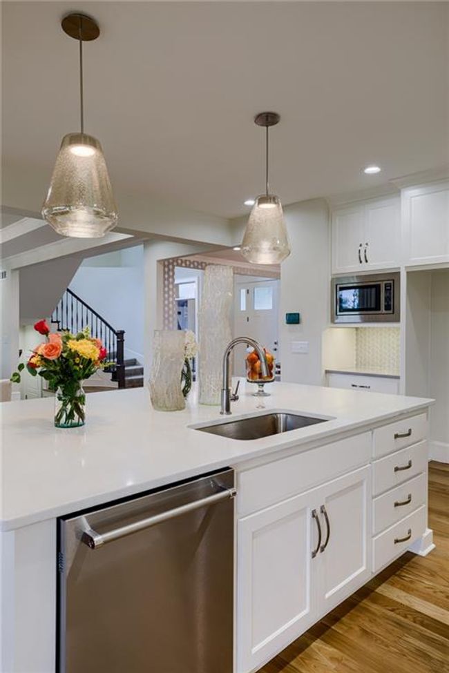 Kitchen featuring appliances with stainless steel finishes, white cabinets, sink, light wood-type flooring, and hanging light fixtures | Image 17