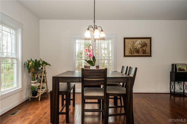 Dining room featuring a notable chandelier, visible vents, dark wood-type flooring, and a healthy amount of sunlight | Image 10