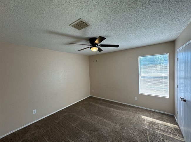 Empty room with a textured ceiling, ceiling fan, and carpet flooring | Image 13