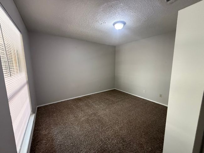 Empty room with dark colored carpet and a textured ceiling | Image 14