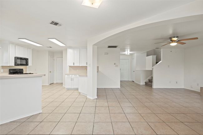 Kitchen featuring white cabinetry, open floor plan, visible vents, and black microwave | Image 7