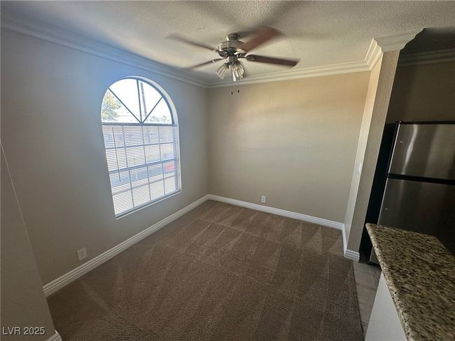 Unfurnished dining area with dark colored carpet, a ceiling fan, ornamental molding, and baseboards | Image 7
