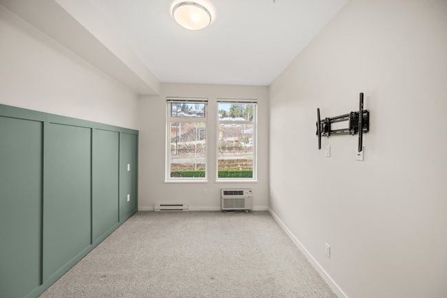 Unfurnished bedroom featuring a baseboard heating unit, light colored carpet, and an AC wall unit | Image 25