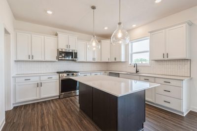 Photo is of the actual home. The spacious kitchen features a large center island, quartz countertops, LVP floors, stainless appliances and more! | Image 3