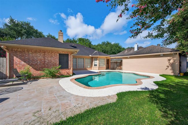 This photo showcases a charming backyard with a well-maintained pool surrounded by a spacious patio area, lush greenery, and a brick and siding exterior. Perfect for outdoor relaxation and entertainment. | Image 39