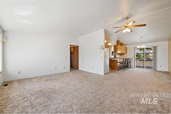 Living area featuring ceiling fan, light colored carpet, and vaulted ceiling | Image 4