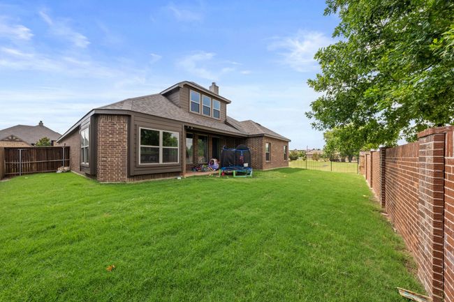 Rear view of property featuring a trampoline, brick siding, a fenced backyard, and a chimney | Image 22