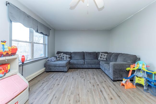 Living room with light wood-style flooring, ceiling fan, a baseboard heating unit, and baseboards | Image 23