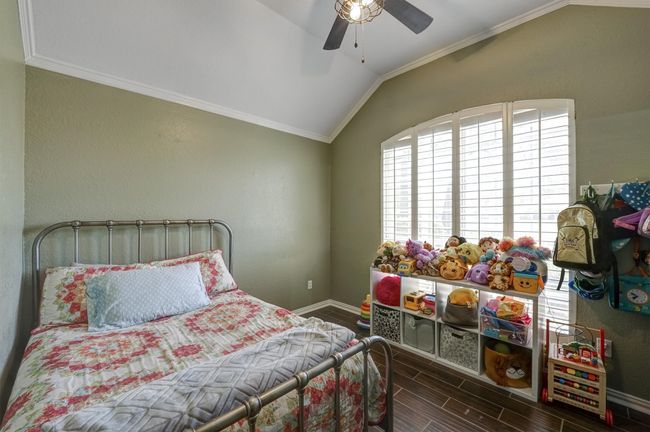 Bedroom with ceiling fan, wood finish floors, ornamental molding, lofted ceiling, and baseboards | Image 16