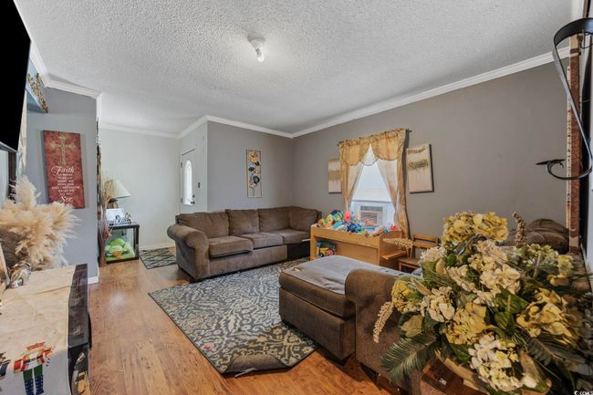 Living area with wood finished floors, ornamental molding, and a textured ceiling | Image 4