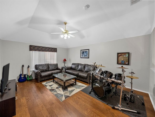 Living room featuring a ceiling fan, a tray ceiling, wood finished floors, and visible vents | Image 31