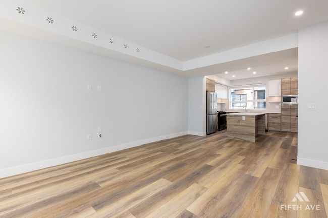 Kitchen with appliances with stainless steel finishes, open floor plan, wood finished floors, recessed lighting, and light countertops | Image 11
