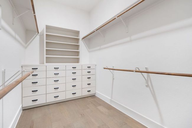 This custom walk-in closet offers a boutique-style experience, complete with thoughtfully designed built-ins, abundant hanging space, and open shelving to keep everything organized and within reach. | Image 18