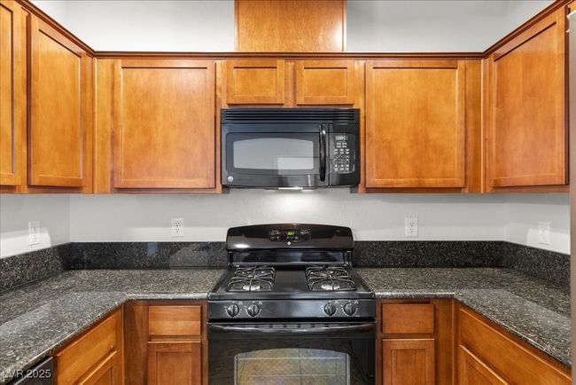 Kitchen with black appliances and brown cabinets | Image 9