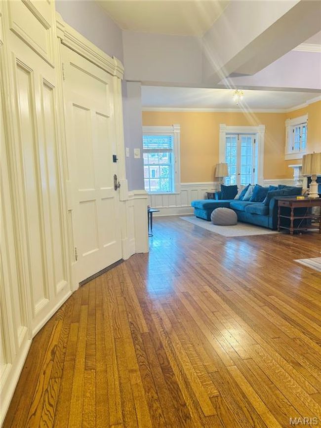 Entryway with light wood-style flooring, crown molding, a decorative wall, and a wainscoted wall | Image 4