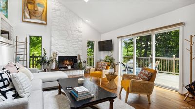 Living room with hardwood / wood-style floors, high vaulted ceiling, and a fireplace | Image 3