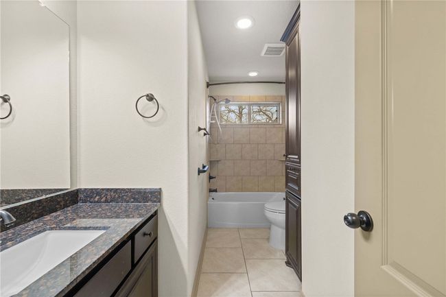 Bathroom with tile patterned flooring, toilet, shower / tub combination, vanity, and visible vents | Image 18
