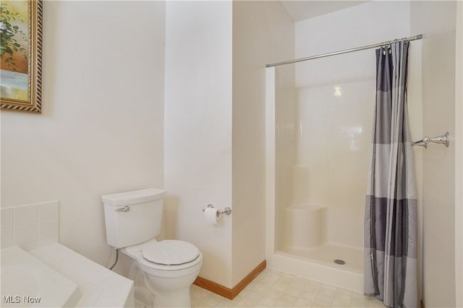 Bathroom featuring curtained shower, toilet, and baseboards | Image 33