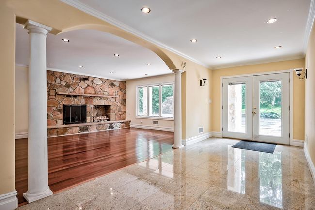 Unfurnished living room featuring crown molding, recessed lighting, granite finish floor, and ornate columns | Image 5