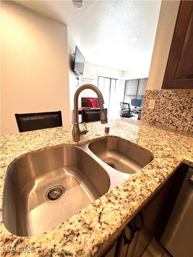 Interior details with light stone countertops, dark brown cabinetry, decorative backsplash, and a sink | Image 18