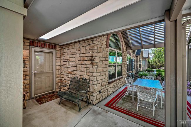 View of exterior entry featuring stone siding, outdoor dining area, and a patio area | Image 21
