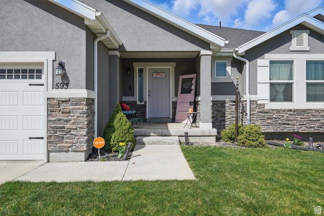 Property entrance with a garage, stucco siding, stone siding, and a lawn | Image 6