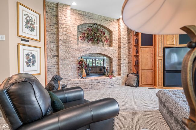 carpeted living room featuring a fireplace, built in features, and brick wall | Image 68