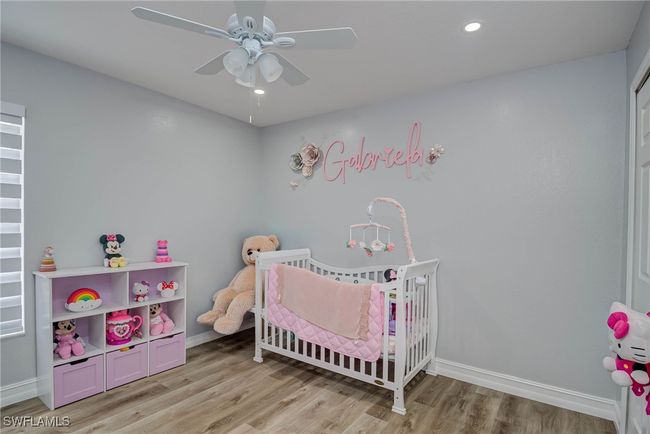 Bedroom with light wood-style floors, a crib, baseboards, ceiling fan, and recessed lighting | Image 13