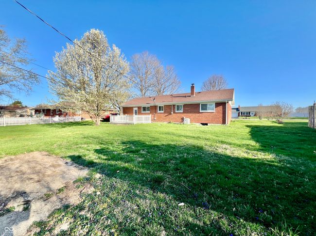 back of property featuring fence, a yard, brick siding, and a chimney | Image 24