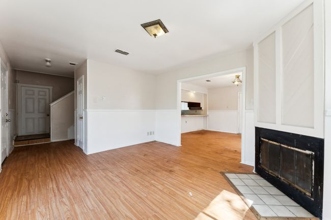 Unfurnished living room featuring a fireplace with flush hearth and light wood finished floors | Image 14