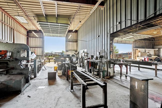 Interior space featuring a towering ceiling, concrete floors, a workshop area, and metal wall | Image 10