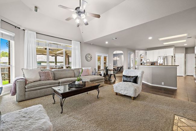 Living room with arched walkways, a ceiling fan, dark tile patterned flooring, recessed lighting, and lofted ceiling | Image 7